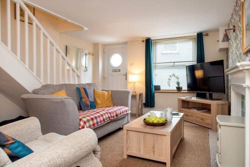 a living room with a couch and a tv at Cosy Cottage - Apple Pie Luxury Escapes in Bere Alston