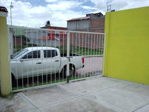a white truck parked behind a fence with a parking meter at CASA ACOGEDORA in Chignahuapan