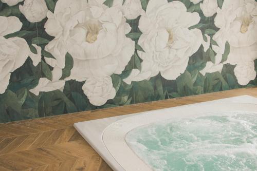una vasca da bagno di fronte a una parete floreale di Hotel Bogliaco a Gargnano