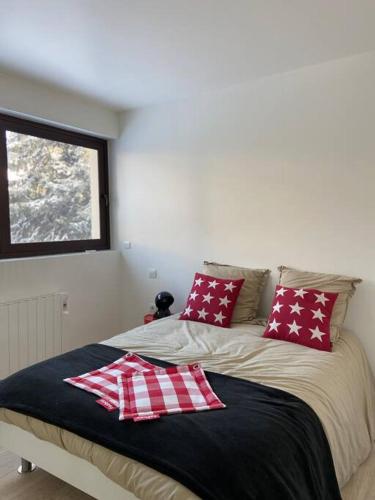 1 cama con almohadas rojas y blancas y ventana en L'Etoile de la Forêt en Bolquere Pyrenees 2000