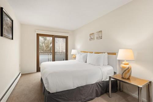 a white bedroom with a large bed and a table at Timber Ridge Unit 3E in Aspen
