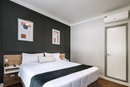 um quarto com uma grande cama branca com paredes pretas em TARATA BOUTIQUE HOTEL em Lima