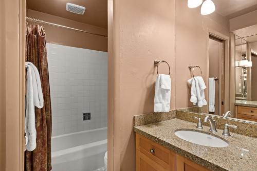 a bathroom with a sink and a mirror and a tub at Silverglo Condominiums Unit 308, Expansive 4 BD Condo, Walking Distance to Town with Pool Access in Aspen