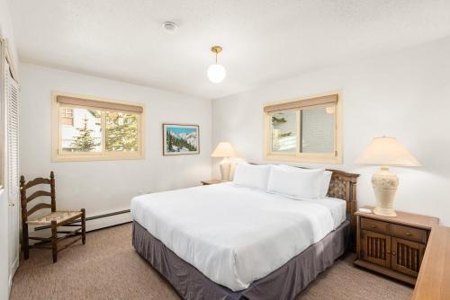a bedroom with a large white bed and two windows at 118 E. Bleeker Street Lower Level, Large Lower-Level Condo in Duplex with Private Deck in Aspen