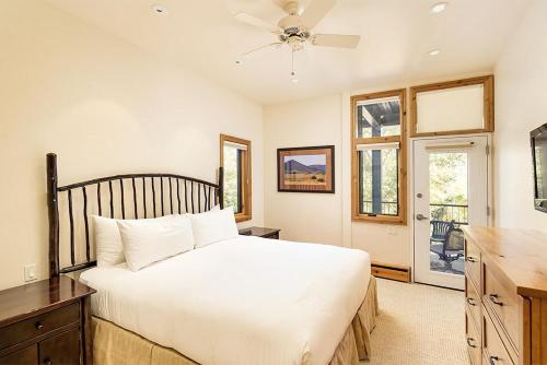 a bedroom with a white bed and a desk and windows at Fifth Avenue Unit 202, 2 Bedroom + Loft Condo, Huge Windows & Views. 2 Blocks to Skiing! in Aspen