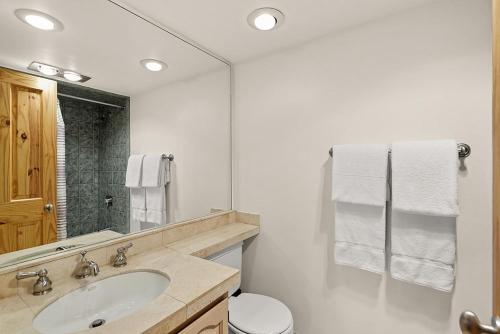 a white bathroom with a sink and a mirror at Chateau Eau Claire Unit 8, Riverfront Condo, Walking Distance to Town in Aspen