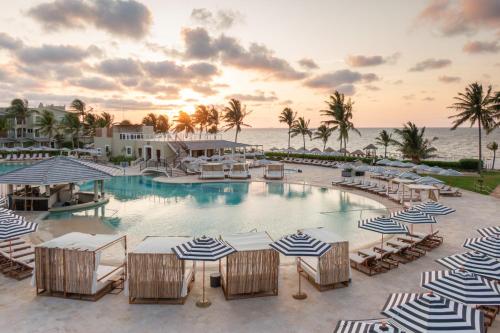a pool with chairs and umbrellas and the ocean at Hyatt Zilara Riviera Maya Adults Only All-Inclusive in Playa del Carmen