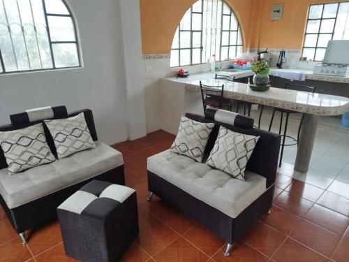 a living room with two chairs and a kitchen at 1 Cuarto independiente individual in Ambato