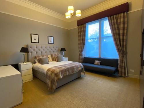 um quarto com uma cama, um sofá e uma janela em WM Apartments em Edimburgo