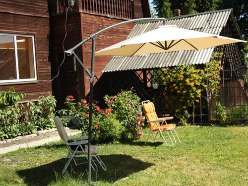 two chairs and an umbrella in a yard at Viesu Māja Arnicāni in Ragaciems