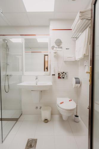 a white bathroom with a toilet and a sink at Hotel Lacu Rosu in Lacu Rosu