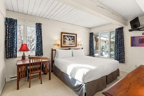 Un dormitorio con una cama y una mesa con una silla. en Chateau Roaring Fork Unit 29, Sunny, Corner Condo with River Views, en Aspen