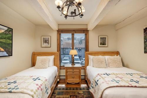1 dormitorio con 2 camas y lámpara de araña en Chateau Roaring Fork Unit 38, Condo with Private Deck, 4 Blocks from Downtown, en Aspen