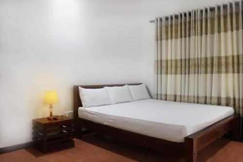 1 dormitorio con 1 cama con cortina y mesa en Flying Peacock Yala, Katharagama,, en Kataragama