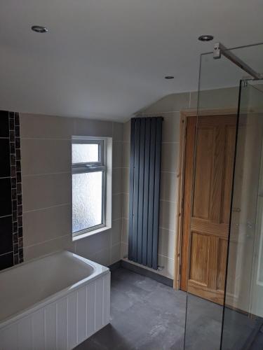 a bathroom with a bath tub and a window at Prospect House - Elegant 4-Bed Family Escape Near Ward Park & Marina in Bangor