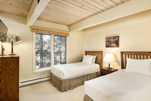a bedroom with two beds and a window at Chateau Eau Claire Unit 18, Spacious Condo Overlooking the River with a Private Deck in Aspen