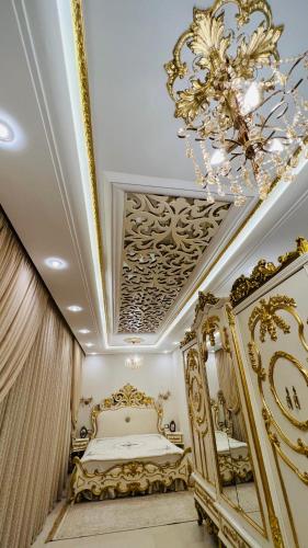 a gold bedroom with a bed and a chandelier at Maison Fathallah in Mahdia