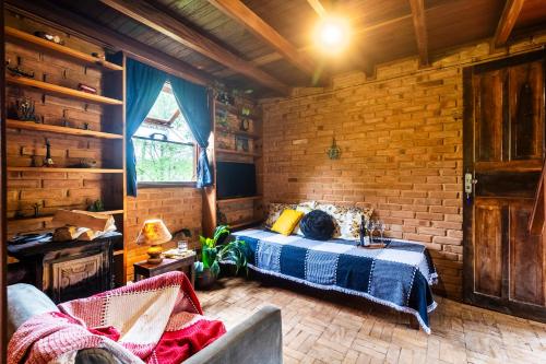 a bedroom with a bed and a brick wall at Sitio Tahiupara in Gonçalves