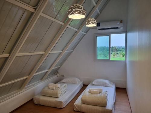 Cette chambre mansardée comprend 2 lits et une fenêtre. dans l'établissement Wind in the Wild Khao Yai, à Nakhon Ratchasima
