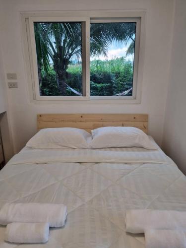 a bed with two pillows in a room with a window at Wind in the Wild Khao Yai in Nakhon Ratchasima