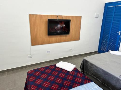 a room with two beds and a tv on a wall at Studio mobiliado na Vila Guilherme - São Paulo/SP in São Paulo