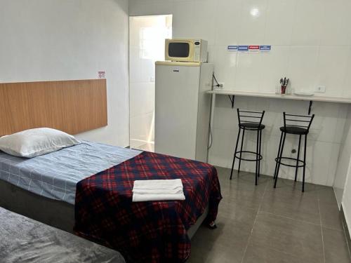 a bedroom with a bed and a kitchen with stools at Studio mobiliado na Vila Guilherme - São Paulo/SP in São Paulo