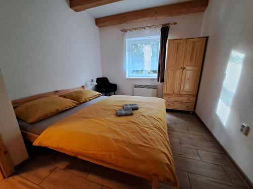 a bedroom with a bed with a yellow bedspread and a window at Chalupa Petra in Dolní Morava