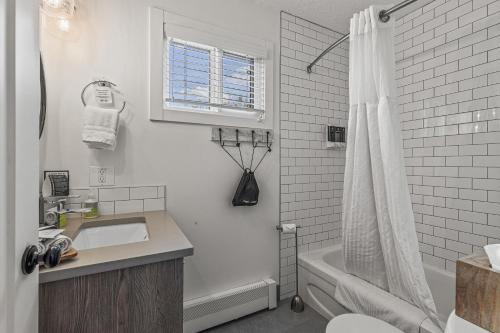 a white bathroom with a sink and a shower at Lamphouse By Basecamp in Canmore