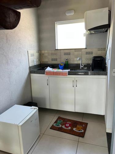 a kitchen with white cabinets and a sink and a window at Pousada Sete Estrelas do Mar in Ilhéus