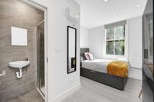 a bathroom with a bed and a sink and a mirror at Hackney Suites in London