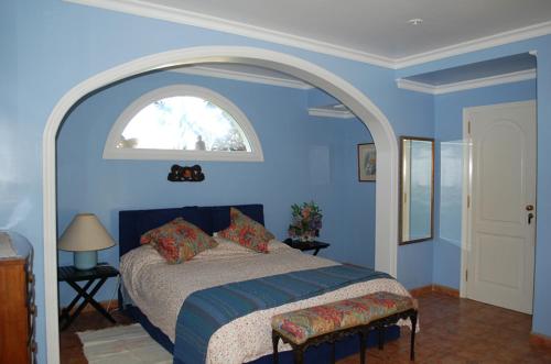 a blue bedroom with a bed and an arched window at Luxury Villa with Pool Sea and Mountain Views in Puerto de la Cruz in La Orotava