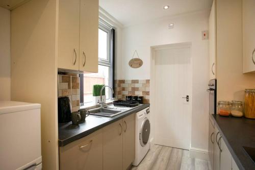 a kitchen with a sink and a washing machine at *Cosy home with parking for you* in Derby