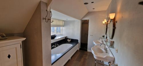 a bathroom with two sinks and a bath tub at Amsterdam Mansion - Suite De Dam in Oostzaan