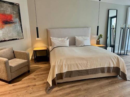 a bedroom with a large bed and a chair at Galerie Hotel in Paderborn