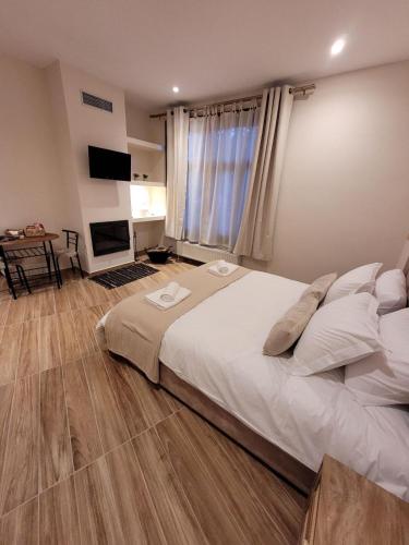 una camera da letto con un grande letto bianco e una televisione di Kleodora Apartments ad Aráchova