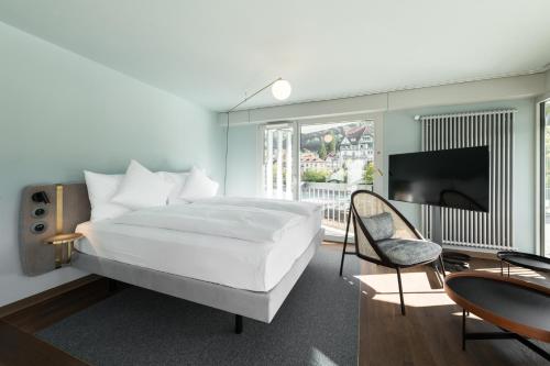 a bedroom with a large white bed and a television at Hotel Aare Thun in Thun