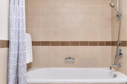 a bathroom with a tub and a shower curtain at Bellavista - High Floor - 1BR - 29 Boulevard - Burj Khalifa & Fountain View in Dubai