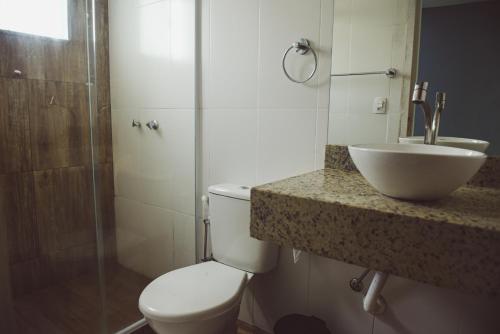 a bathroom with a toilet and a sink and a shower at Pousada Xerxes in Arraial do Cabo