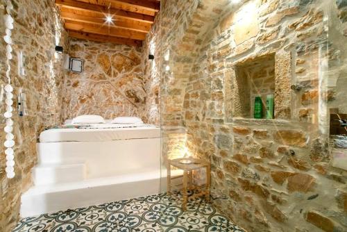a stone walled bathroom with a tub and a stool at Almond Blossom Cottage 2 in Philotium