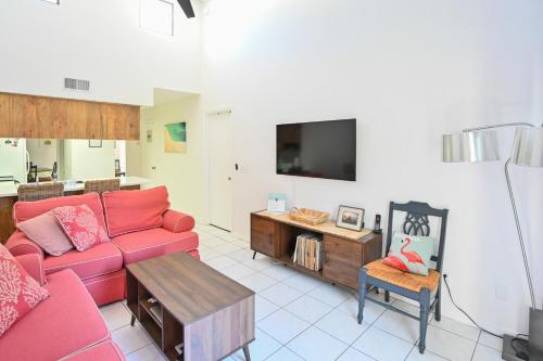 a living room with a red couch and a tv at Satellite Beach Townhome with Patios 2 Mi to Beach in Satellite Beach