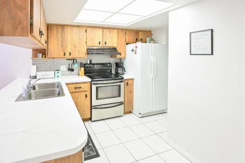 a kitchen with wooden cabinets and a white refrigerator at Satellite Beach Townhome with Patios 2 Mi to Beach in Satellite Beach