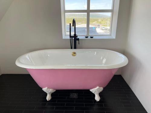 W łazience z oknem znajduje się różowa wanna. w obiekcie Hótel Goðafoss Fosshóll w mieście Godafoss