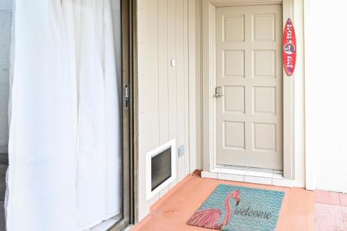 a door with a pink flamingo rug in front of it at Satellite Beach Townhome with Patios 2 Mi to Beach in Satellite Beach