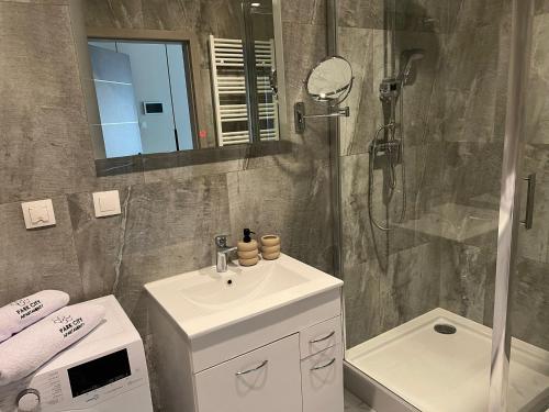 a bathroom with a sink and a shower with a mirror at Apartament 4 Park City in Ostrów Wielkopolski