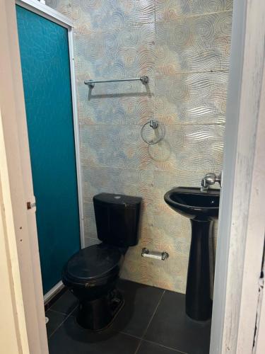 a bathroom with a black toilet and a sink at Oasis at Eco Hostal Villa Canada in Playa Punta Arena