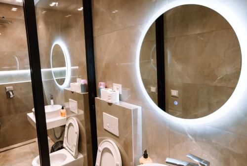 een badkamer met een toilet en een ronde spiegel bij Modern Apartments near Center - THE NEST in Tirana