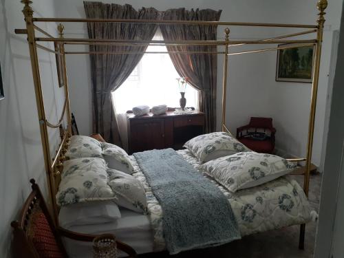 een slaapkamer met een hemelbed met kussens en een raam bij 58 Boom Street Holiday Home. in Parys