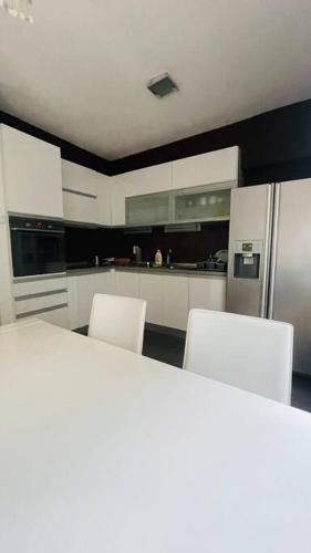 uma cozinha com 2 cadeiras brancas e um frigorífico em Skopje Centre apartment em Skopje