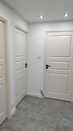 two doors in a room with white walls and tile floors at APARTAMENT "Opawska Przystań" in Głuchołazy