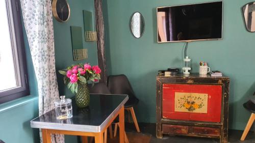 una camera con tavolo, TV e vaso di fiori di Appartement typique Rouen centre tout confort a Rouen
